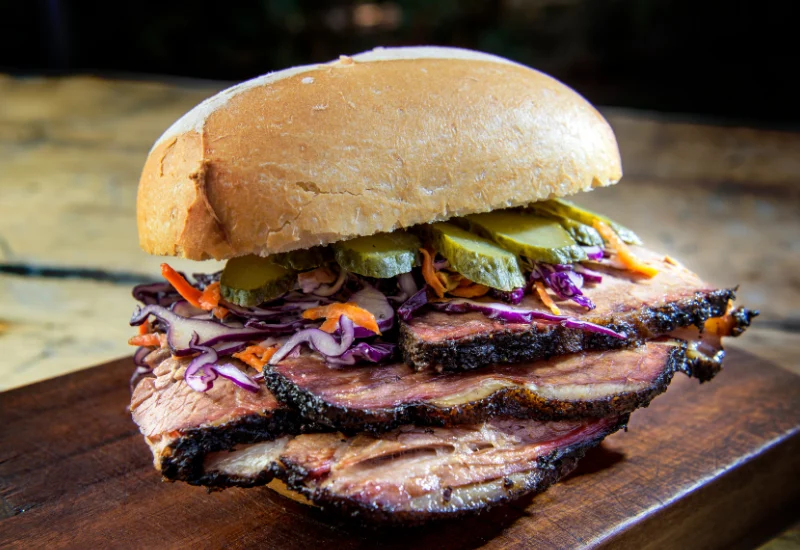 The Brooklyn Brisket Sandwich with tender slow-smoked brisket piled on fresh rye bread and topped with homemade sauce.